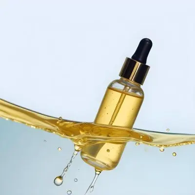A Glass Bottle With A Dropper Dispenser Filled With A Golden Colored Liquid Resting On A Reflective Surface With Water Droplets 2