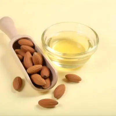 A Glass Jar Filled With Golden Colored Oil Surrounded By Several Whole Almonds On A Light Background 16 4601