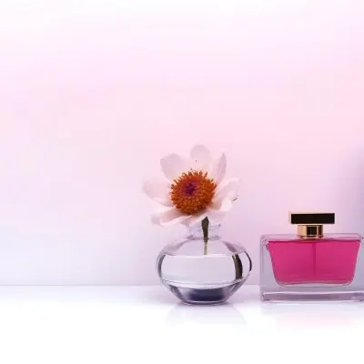 A Perfume Bottle And A Vase With Flowers On A White Surface Pink Background Studio Shot Product Photography Clean And Minimalist Composition 47 5a18