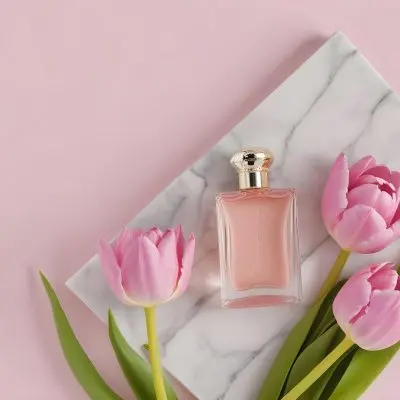 A Perfume Bottle On A Marble Tile Surrounded By Pink Tulips With Green Leaves All Against A Green Background 37 A5c6