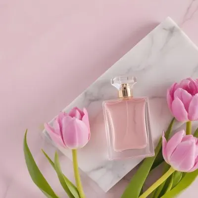 A Perfume Bottle On A Marble Tile Surrounded By Pink Tulips With Green Leaves All Against A Green Background 43 706d