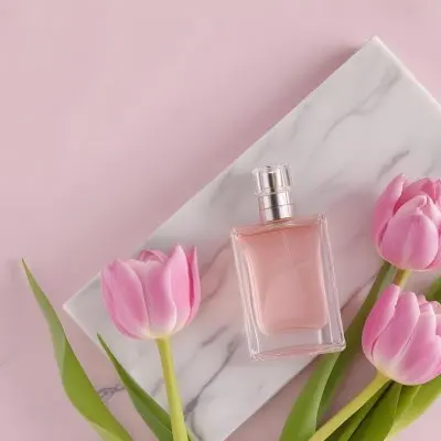 A Perfume Bottle On A Marble Tile Surrounded By Pink Tulips With Green Leaves All Against A Green Background 46 D60c