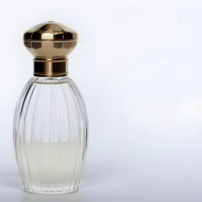 A Perfume Bottle With A Transparent Cap Transparent Glass With Vertical Stripes Half Full Of Transparent Liquid In A White Background 14 04f6