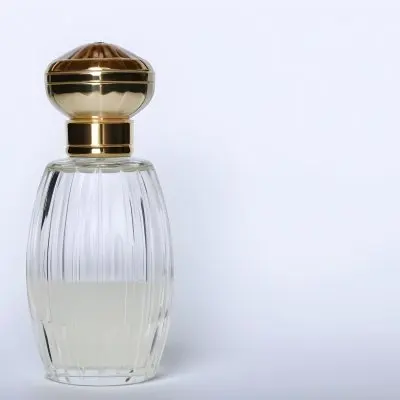 A Perfume Bottle With A Transparent Cap Transparent Glass With Vertical Stripes Half Full Of Transparent Liquid In A White Background 18 A69b
