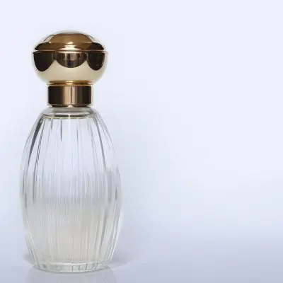 A Perfume Bottle With A Transparent Cap Transparent Glass With Vertical Stripes Half Full Of Transparent Liquid In A White Background 20 5f3f