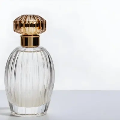 A Perfume Bottle With A Transparent Cap Transparent Glass With Vertical Stripes Half Full Of Transparent Liquid In A White Background 27 F9e0