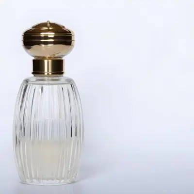 A Perfume Bottle With A Transparent Cap Transparent Glass With Vertical Stripes Half Full Of Transparent Liquid In A White Background 4 9b60