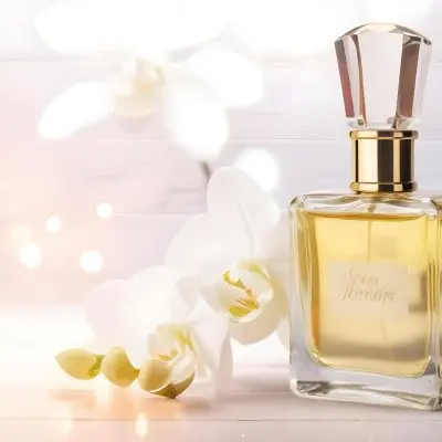 A Perfume Bottle With A Wooden Cap And A White Orchid On A White Wooden Surface With Bokeh Lights In The Background 41 Ca12
