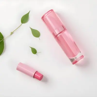A Pink Glass Bottle And A Pink Lipstick Tube On A White Background With A Green Leaf 6 De85