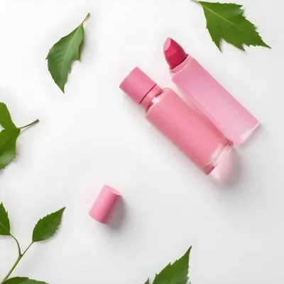 A Pink Glass Bottle And A Pink Lipstick Tube On A White Background With A Green Leaf 9 C49f