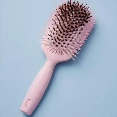A Pink Hairbrush With Bristles And A Handle On A Light Blue Background 3