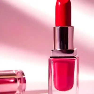 A Red Lipstick With A Metallic Pink Case The Cap Is Off And Lying On The Side In A Pink Background With Soft Light 8 3f19