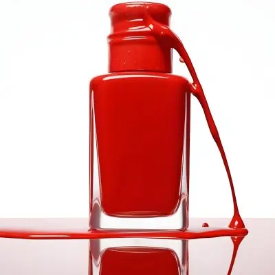 A Red Nail Polish Bottle With Nail Polish Dripping Down The Side On A Red Background 7 5836