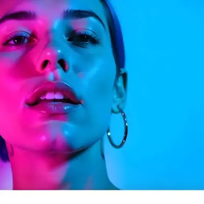 A Tanned Woman 25 Years Old With Blue Hair And Hoop Earrings Half Of Her Face Is Illuminated With Pink Light And The Other Half With Blue Light In A Blue Background 11 Ddc0