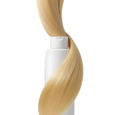A White Bottle Of Shampoo With A Pump Wrapped In A Strand Of Long Blonde Hair On A White Background 6 Edff
