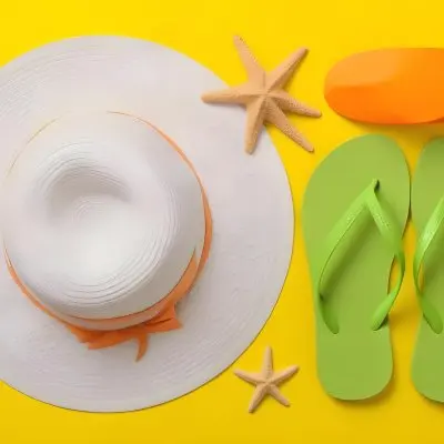 A Yellow Hat A Starfish An White Sunscreen And White Flip Flops On A Orange Background 37 233c
