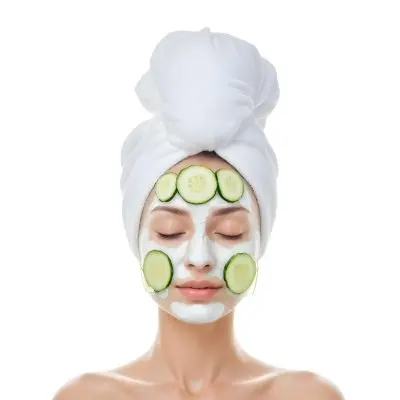 A Young Caucasian Woman With Her Eyes Closed Wearing A White Towel On Her Head And Having Slices Of Cucumber On Her Face In A Spa Room With Soft Lighting 22 82cf