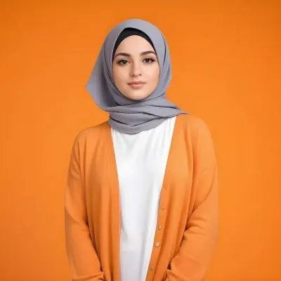 A Young Middle Eastern Woman With Dark Hair Wearing A Gray Hijab A White Sweater And A Orange Cardigan Standing Against A Orange Background 7 C2c5