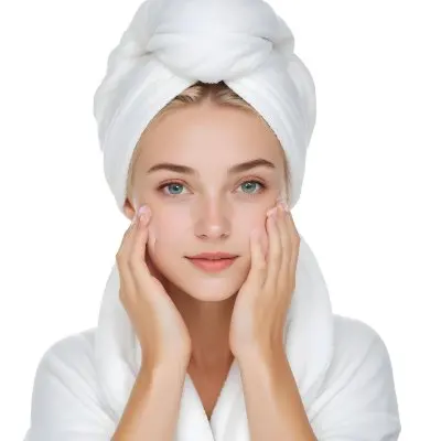 A Young Woman With Fair Skin And Short Blonde Hair Wearing A White Towel On Her Head Gently Washing Her Face With Her Hands In A Bright Bathroom 4 06e0