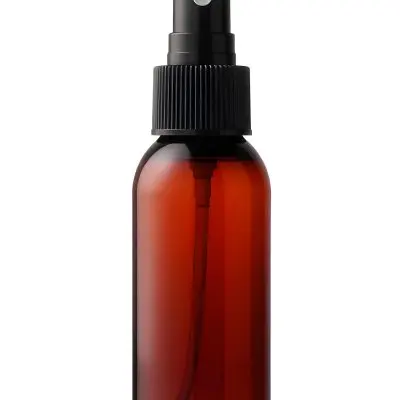 An Amber Glass Spray Bottle With A White Spray Nozzle The Bottle Is Empty The Background Is Black 13 9a55
