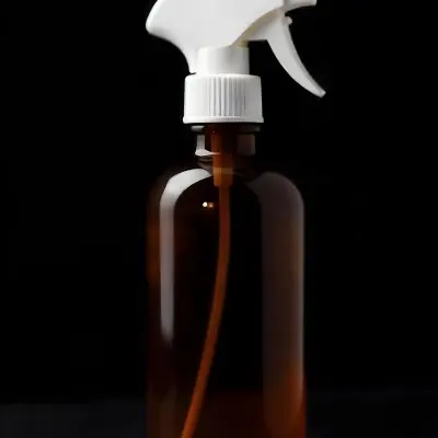 An Amber Glass Spray Bottle With A White Spray Nozzle The Bottle Is Empty The Background Is Black 14 5f68