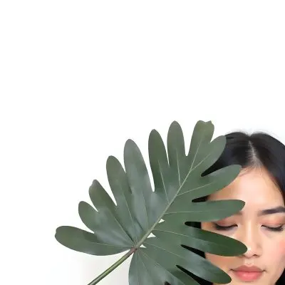 An Asian Woman 23 Years Old With Black Hair Holding A Green Leaf In Front Of Her Face Eyes Closed Black Background 83 C19d