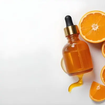 An Orange Bottle Of Facial Oil Serum With A Dropper Surrounded By Sliced Oranges On A White Background 5 C3c7