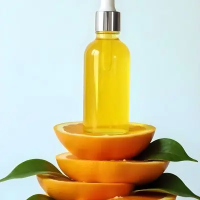 An Orange Fruit With Sliced Segments Green Leaves And A Bottle Of Yellow Liquid On A Light Blue Background 5 D959