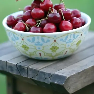 A Bowl Full Of Red Cherries With A Red Leaf On A Wooden Table With A Blurred Red Background 14 F3ca