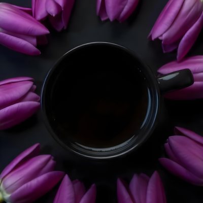 A Black Cup Of Black Coffee Surrounded By Purple Tulips On A Black Background 47 6272