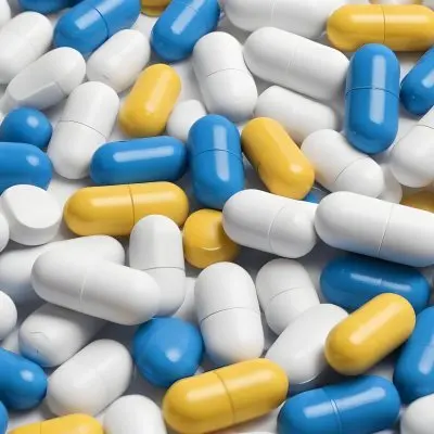 Pile Of Blue White And Yellow Pills And Capsules Pharmaceutical Drugs Medicine Health And Wellness Concept 2 5a87