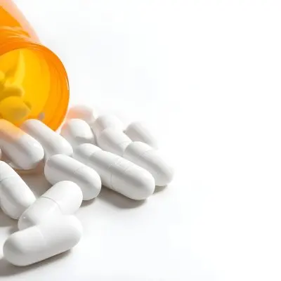 White Pills Spilling Out Of An Orange Pill Bottle On A White Surface Studio Shot 3 0e86