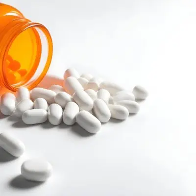 White Pills Spilling Out Of An Orange Pill Bottle On A White Surface Studio Shot 7 C309