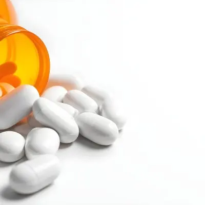 White Pills Spilling Out Of An Orange Pill Bottle On A White Surface Studio Shot 9 901c