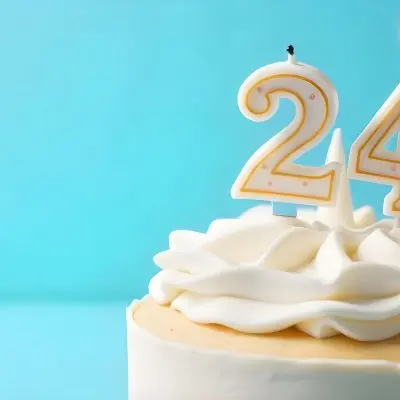 A Birthday Cake With White Frosting And A Candle In The Shape Of The Number 24 Light Blue Background 23 A387