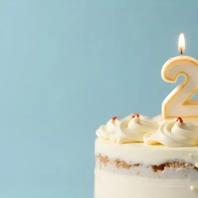 A Birthday Cake With White Frosting And A Candle In The Shape Of The Number 24 Light Blue Background 4 Daf8