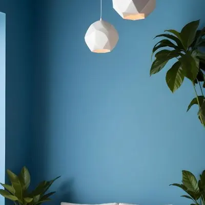A Modern Living Room With A White Sofa A Potted Plant And Geometric Pendant Lights Hanging From The Ceiling Against A Blue Wall 23 F90f