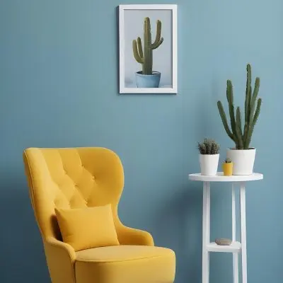 Yellow Armchair With A White Frame On The Wall And A White Table With Cactuses In A Blue Room 7 09de