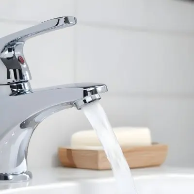 A Chrome Faucet With Water Running In A White Sink With A Soap Dish In The Background 2 66d6