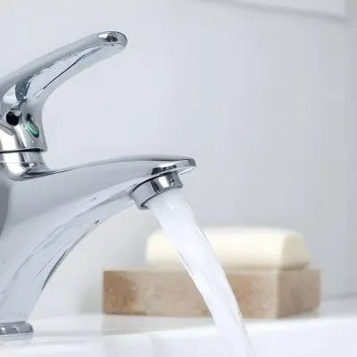 A Chrome Faucet With Water Running In A White Sink With A Soap Dish In The Background 8 7930
