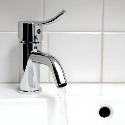 Chrome Faucet With Running Water Over A White Sink In A Bathroom With White Tiles 20 5ac2