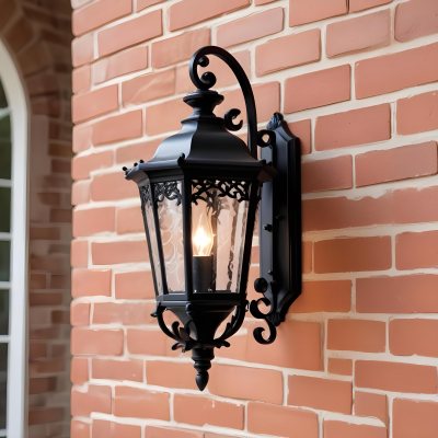 An Ornate Black Metal Outdoor Wall Sconce With A Glass Pane Design Mounted On A Brick Wall 4 00f0