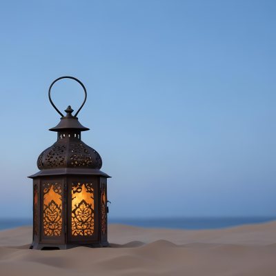 An Ornate Metal Lantern With Intricate Floral Cutouts Casting A Warm Glow On A Sandy Surface Against A Soft Gradient Blue Background 28 0c73