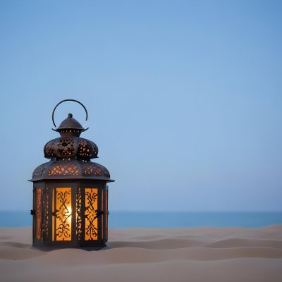 An Ornate Metal Lantern With Intricate Floral Cutouts Casting A Warm Glow On A Sandy Surface Against A Soft Gradient Blue Background 30 D7e2
