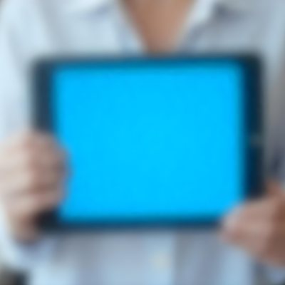 A Person Holding A Tablet With A Blank Blue Screen The Background Is Blurred And Out Of Focus The Person Is Wearing A White Shirt 4 1010